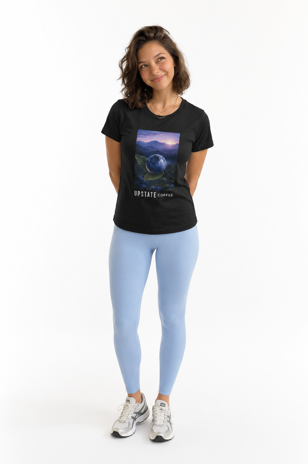Woman wearing a black t-shirt with a graphic design and light blue leggings on a white background