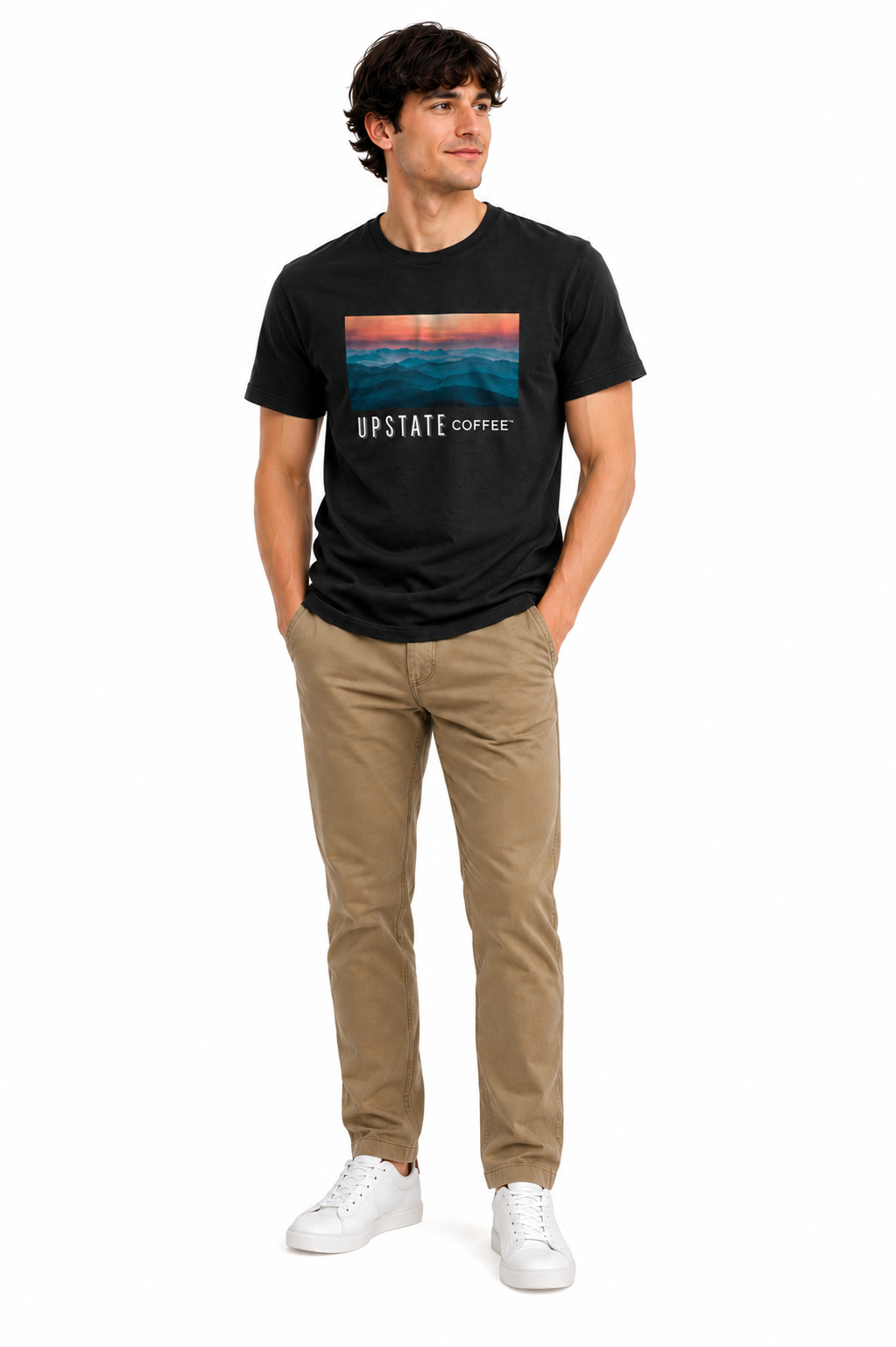 Male model wearing a black tshirt with an upstate coffee mountain scene graphic design and khaki pant on a white backdrop