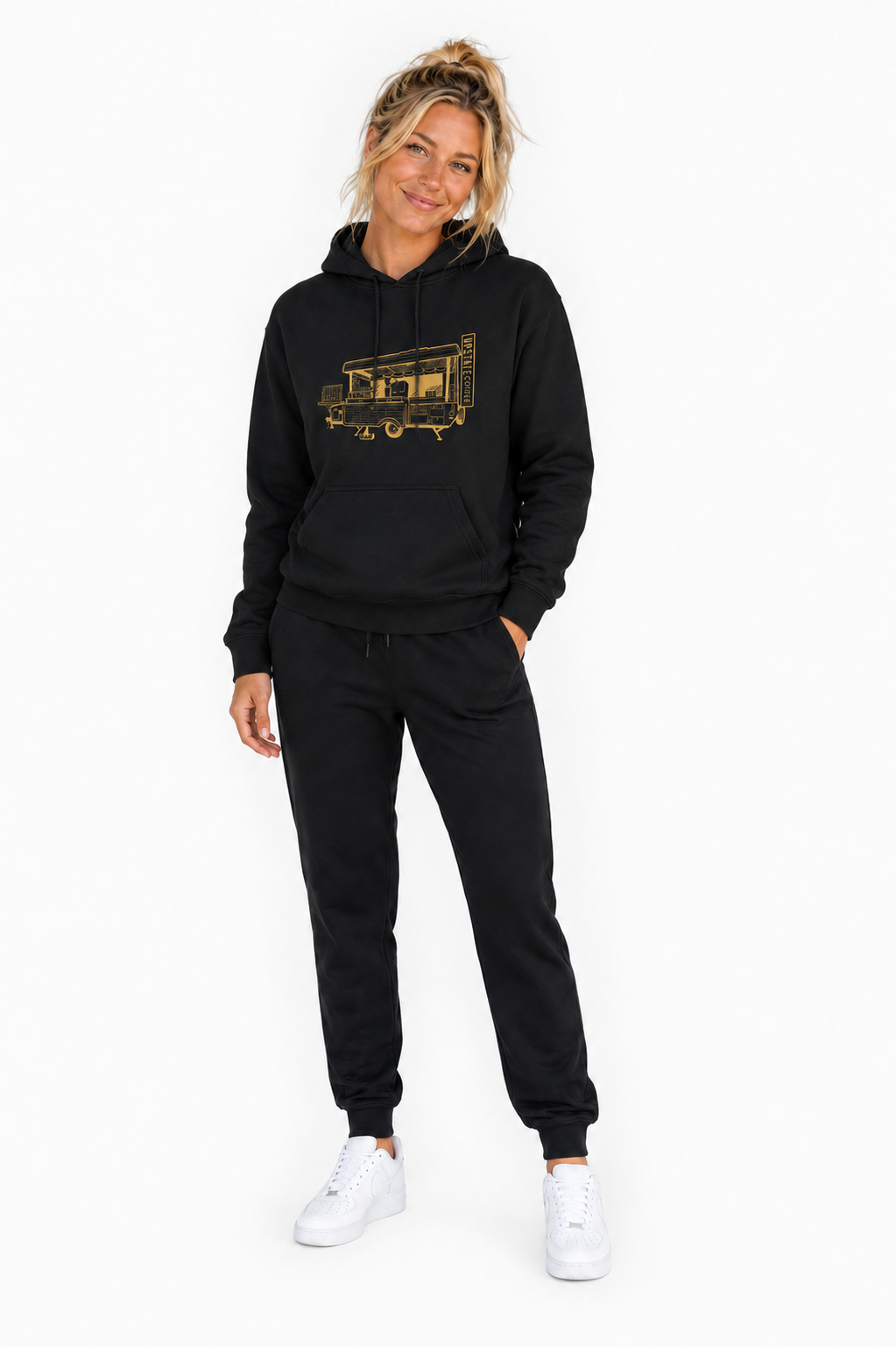 Female model wearing a black Upstate Coffee Hoodie with original camper cafe and pants on a white background